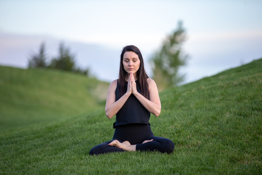 Yeşil çayırda oturarak meditasyon yapan kişi
